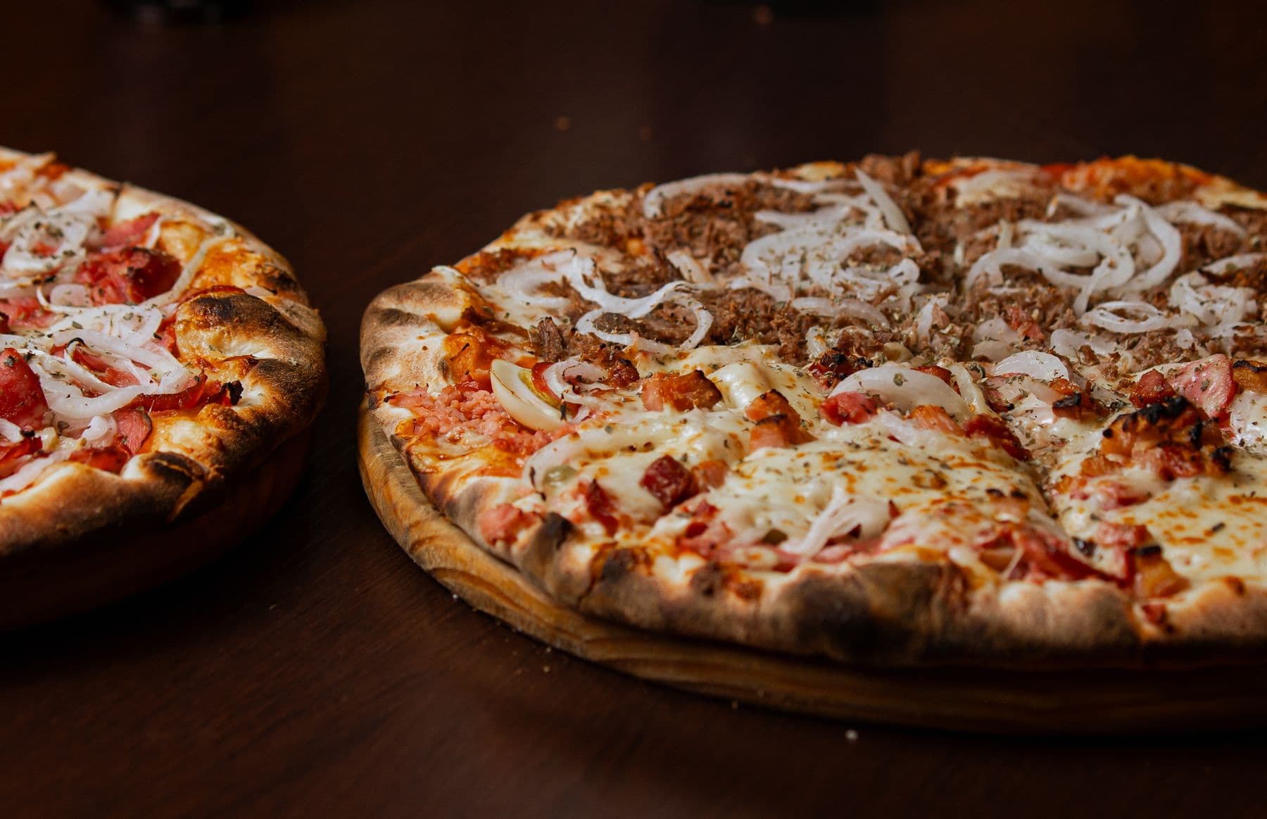 Two thick-crust pan pizzas on a dark table